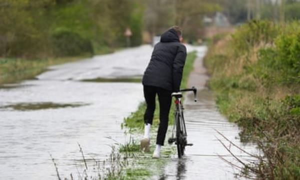 A person pushes a bike through flood water in Littlehampton, West Sussex, an area that falls under Southern Water, after the River Arun burst its banks in April 2024.